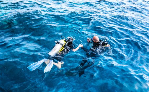 diving instructor holding a disciple's hand in blue water