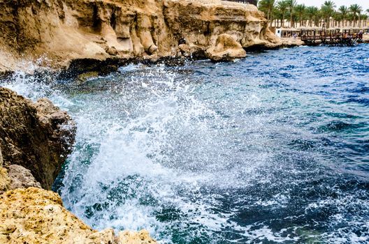 splashing waves of the surf crashing against the rocks on the beach of the red sea