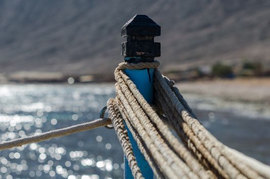 ropes on a pole against the blue sea and mountains close up