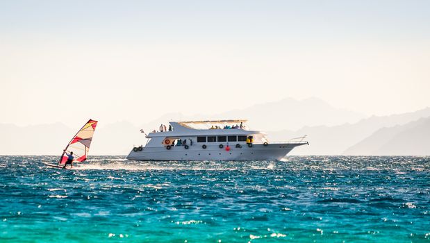 big boat and a surfer in the sea on the background of a rocky coast in Egypt Dahab
