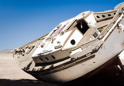 old yacht lies on the sand in the desert against the blue sky