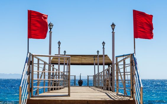 platform on the beach with lanterns and red flags on the background of the sea in Egypt