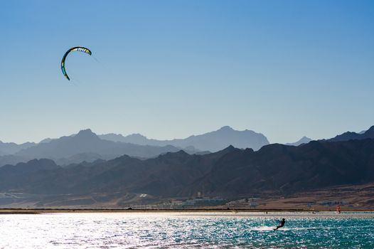 kitesurfer rides in the Red Sea on the background of a rocky coast in Egypt Dahab