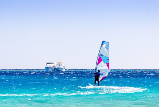 surfer rides in the Red Sea against the backdrop of two ships in Egypt Dahab