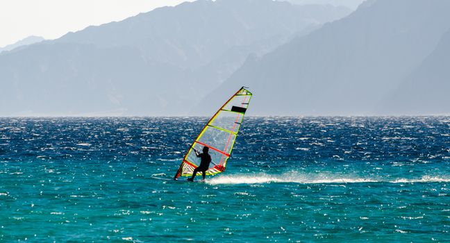 windsurfer on the background of high mountains rides on the waves of the Red Sea in Egypt Dahab