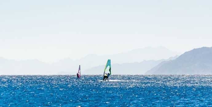 surfers ride in the Red Sea in Egypt against the backdrop of the rocky coast