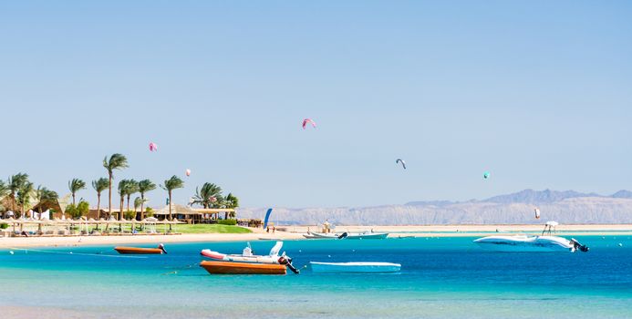 hotel with palm trees on the Red Sea in Egypt with boats and kite surfers