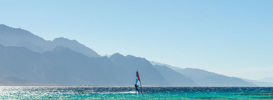 windsurfer rides in the Red Sea against the backdrop of high rocky mountains in Egypt