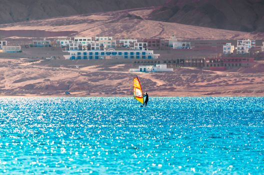one surfer with a sail on a rocky shore and hotels in the Red Sea in Egypt