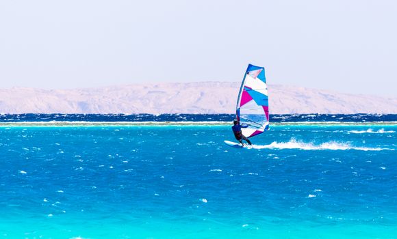 surfer rides in the Red Sea on the background of the rocky coast in Egypt Dahab