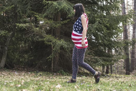 Pregnant woman in the forest. American national flag shirt