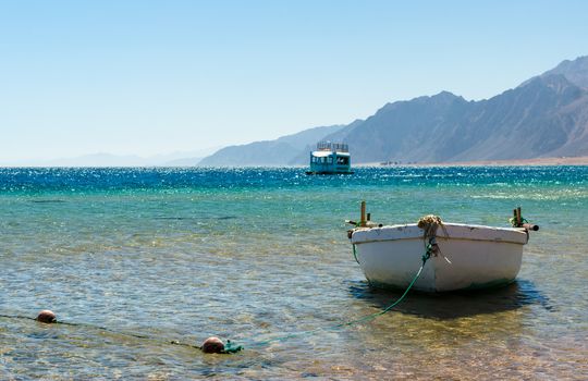 old wooden fishing boat in the sea against the backdrop of the high rocky mountains in Egypt Dahab