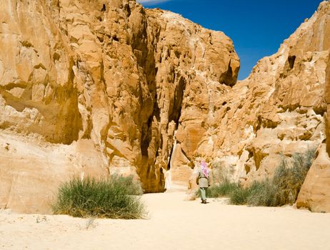 bedouin in white goes in the canyon in the desert among the rocks