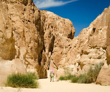 bedouin in white goes in the canyon in the desert among the rocks