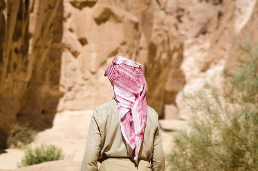 bedouin in white goes in the canyon in the desert among the rocks