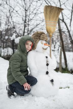Snowman and child in the yard. Winter