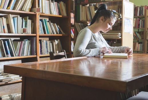 Student girl in a library. Looking at book