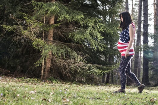 Pregnant woman in the forest. American national flag shirt