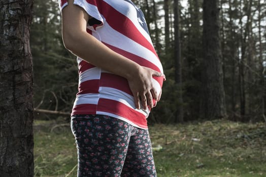 Pregnant woman in the forest. American national flag shirt