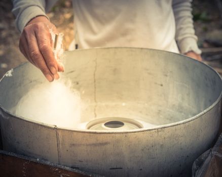 Close-up Asian hand rolling cotton candy in floss machine in Vietnam. Process of street food making