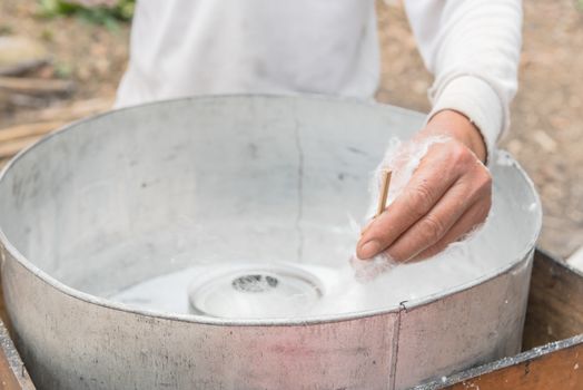 Close-up Asian hand rolling cotton candy in floss machine in Vietnam. Process of street food making