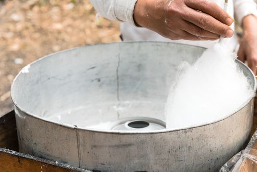 Finished puffy white cotton candy in floss machine in Vietnam. Process of street food making