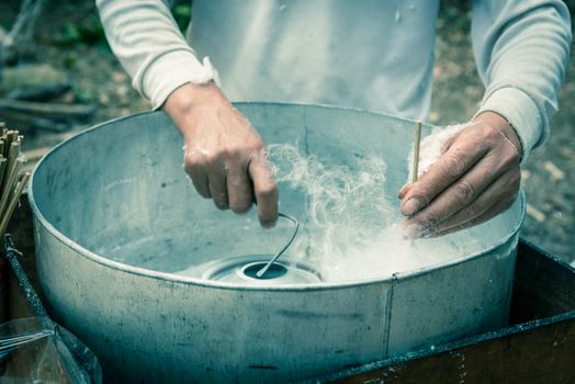 Vintage tone close-up Asian hand rolling cotton candy in floss machine in Vietnam. Process of street food making