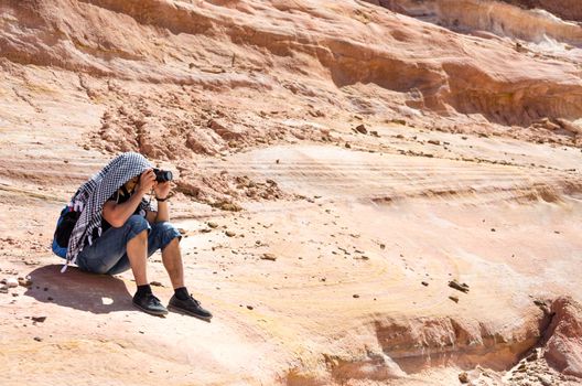 photographer takes pictures sitting on a rock in Egypt Dahab