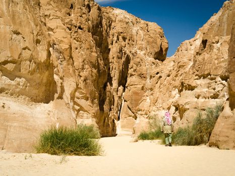 bedouin in white goes in the canyon in the desert among the rocks