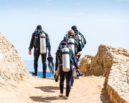 divers with equipment for diving under the water go to the sea on the sky with clouds