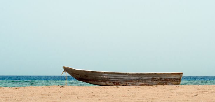 old boat in the sand against the background of the sea and the horizon
