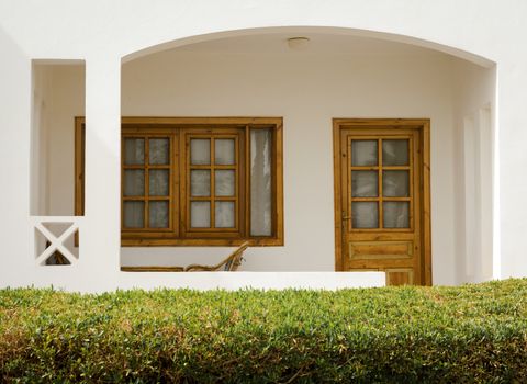 white holiday house with a bush with green leaves nearby