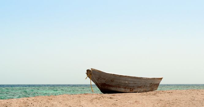 old boat in the sand against the background of the sea and the horizon