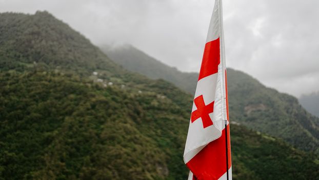 Beautiful view to waving flag of Georgia against the background of the Caucasian mountains