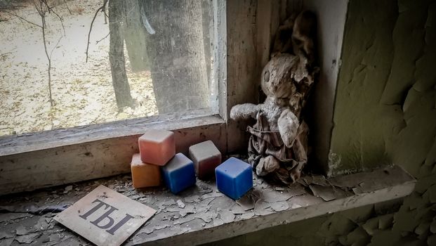 russian word you on paper next to an old doll and colored dusty cubes on a windowsill in an abandoned house in Chernobyl