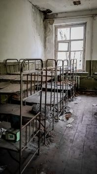 empty children's beds in an abandoned kindergarten house with peeling walls in Chernobyl