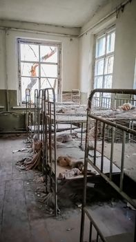empty children's beds in an abandoned kindergarten house with peeling walls in Chernobyl