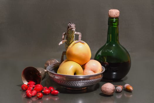 still life with a striped female Yemeni chameleon sitting on a green apple next to a green bottle and melchior glass