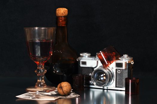 nostalgia still life with an old-fashioned camera brown bottle of alcohol rare photos and walnut