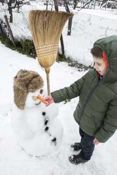 Snowman and child in the yard. Winter