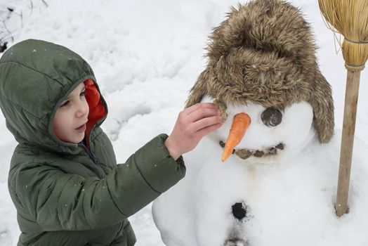 Snowman and child in the yard. Winter