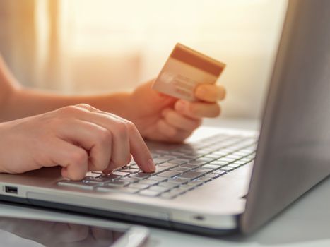 Online shopping concept. Close-up woman's hands holding credit card and using laptop keyboard for online shopping