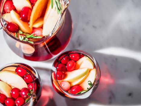 Winter sangria on tabletop with gray linen tablecloth. Glasses of sangria with fruit slice, cranberry and rosemary. Copy space for text or design. Top view or flat lay. Horizontal.