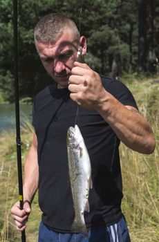 Fisherman caught a fish in mountain dam. Bulgaria