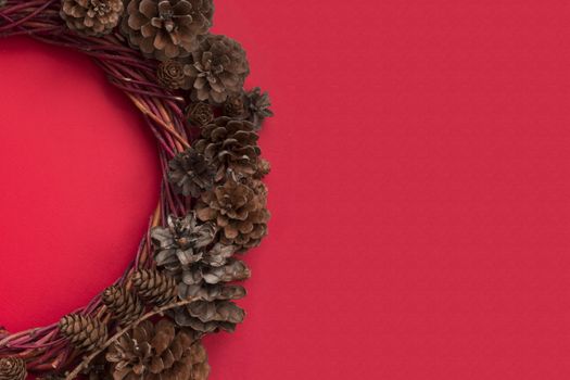 Christmas natural eco style spruce pine cone wreath over red background flat lay top view with copy space for text