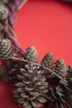 Christmas natural eco style spruce pine cone wreath over red background with copy space for text
