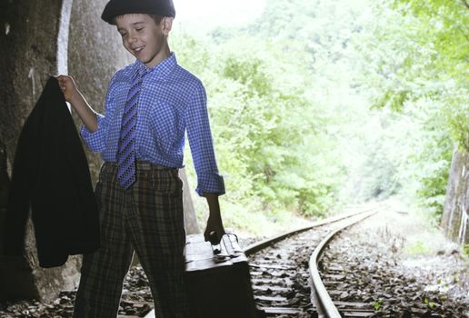 Child walking on railway road with vintage siutcase.