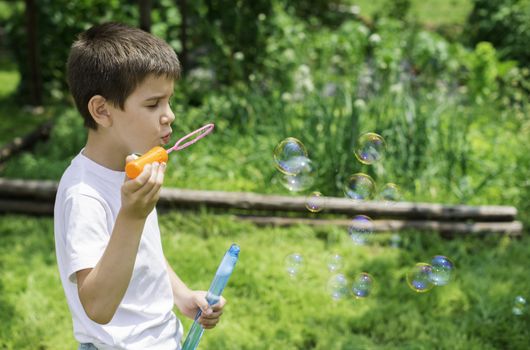 Child makes bubbles. Green park