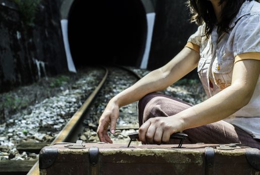 Woman and vintage suitcase on railway road and tunnel. 