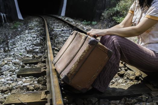 Woman and vintage suitcase on railway road and tunnel. 